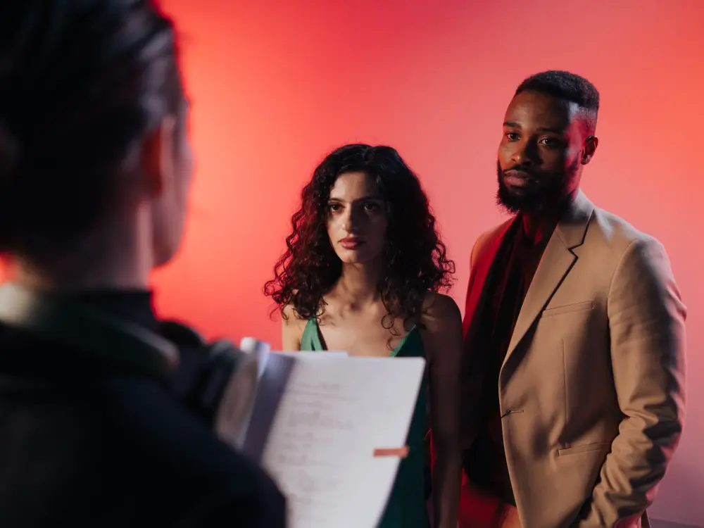 Two performers reading a script under warm studio light