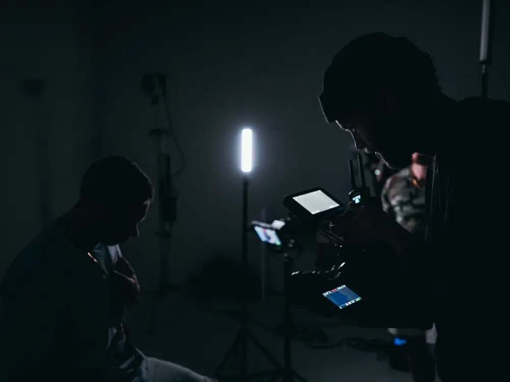 Cinematographer operating a camera in a low-lit finishing room