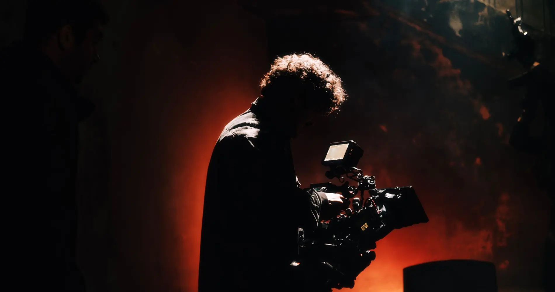 Camera operator silhouetted against warm backlight on set