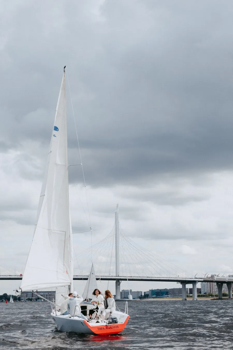 A group sailing a white boat near a bridge