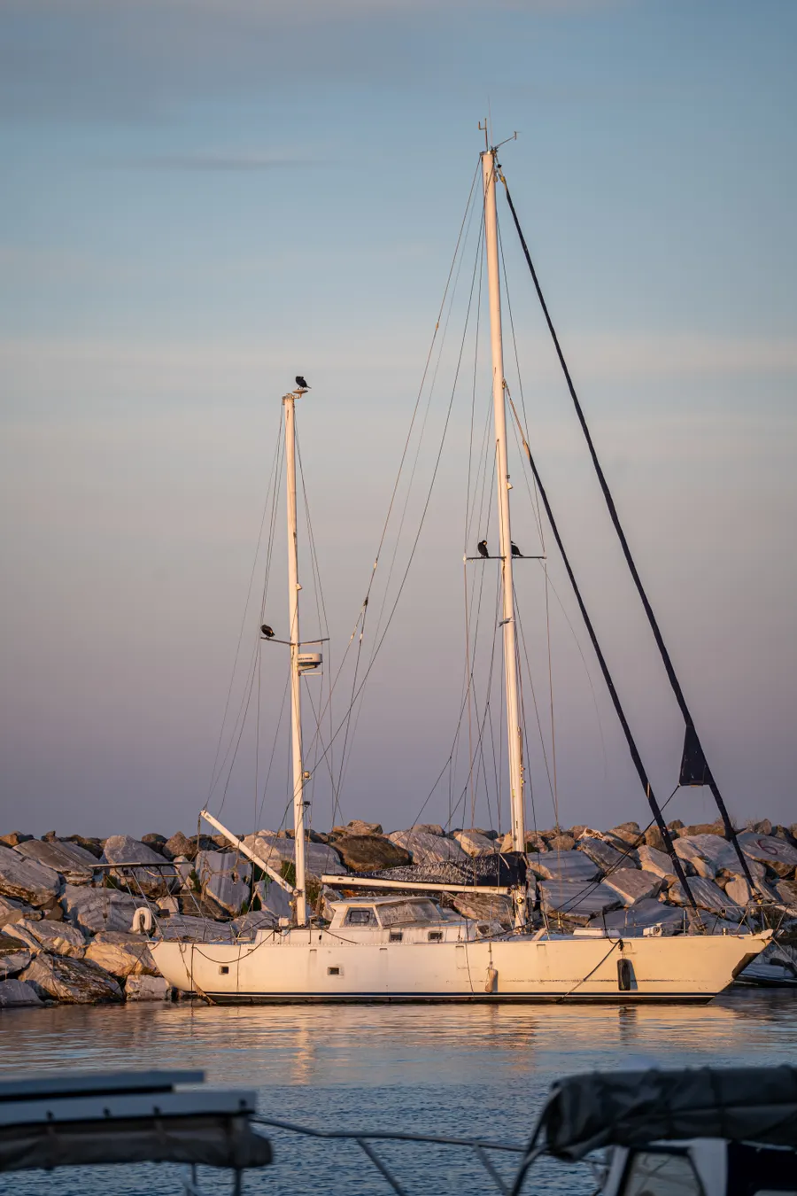 Sailing boat moored beside a rocky shore at sunset
