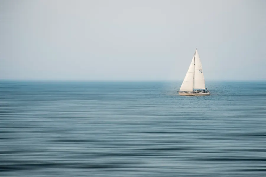 A sailing boat gliding across a calm blue sea