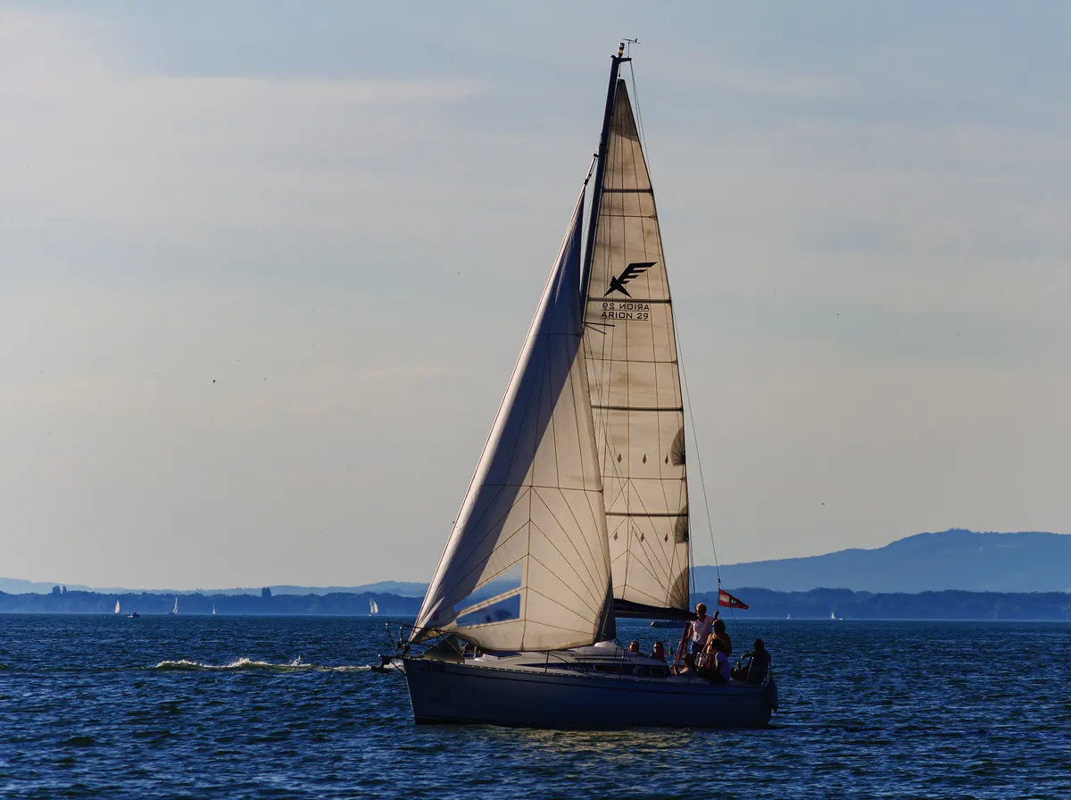 Sailing boat on calm water with mountains behind