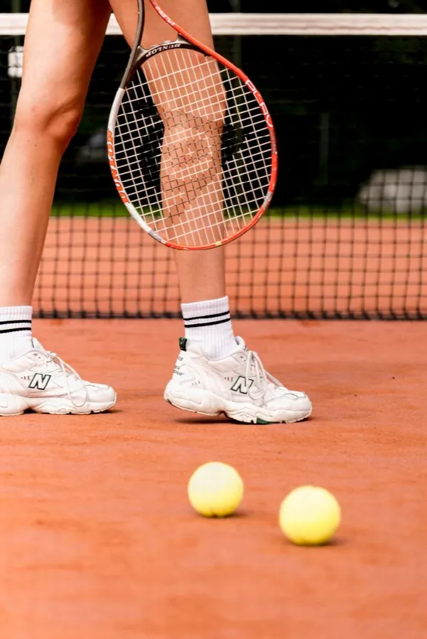 Close view of a player's feet and racket on crushed clay