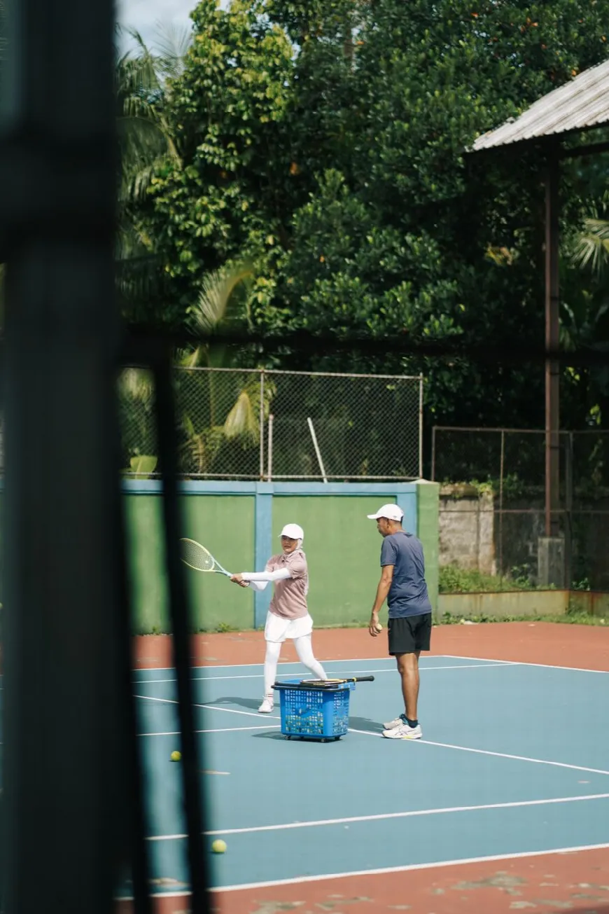 A coach working through footwork with a player during an outdoor session