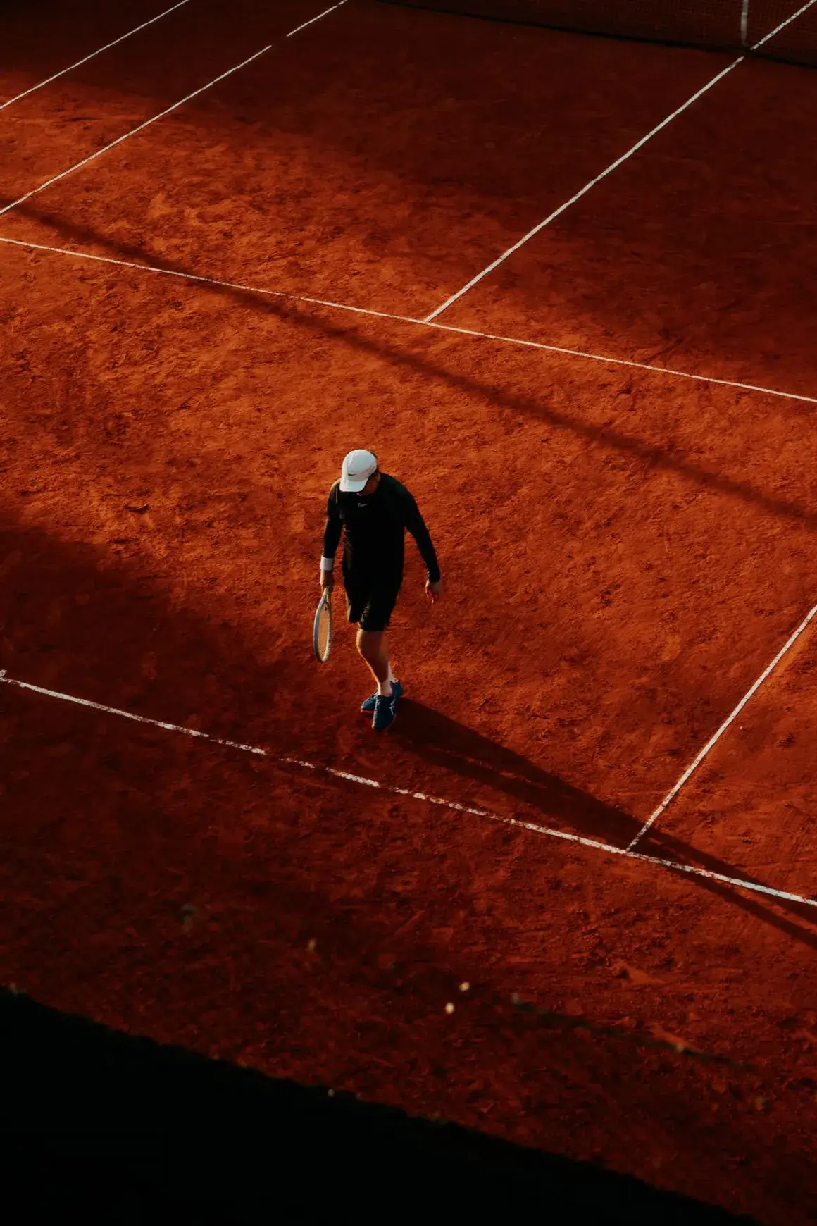Aerial view of a player alone on a red clay court