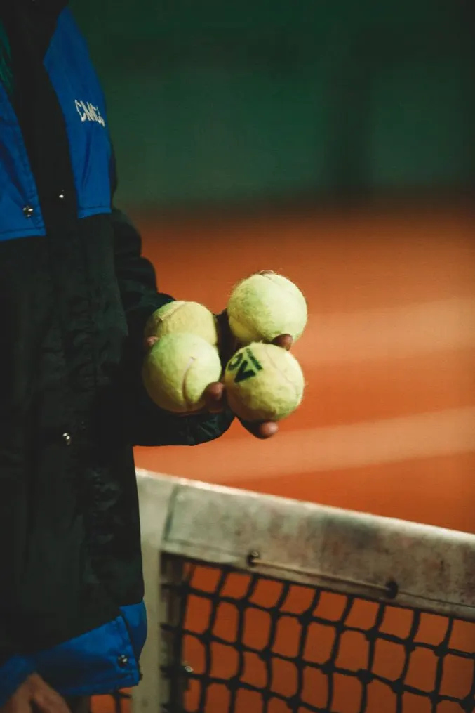 A hand holding practice balls above the net